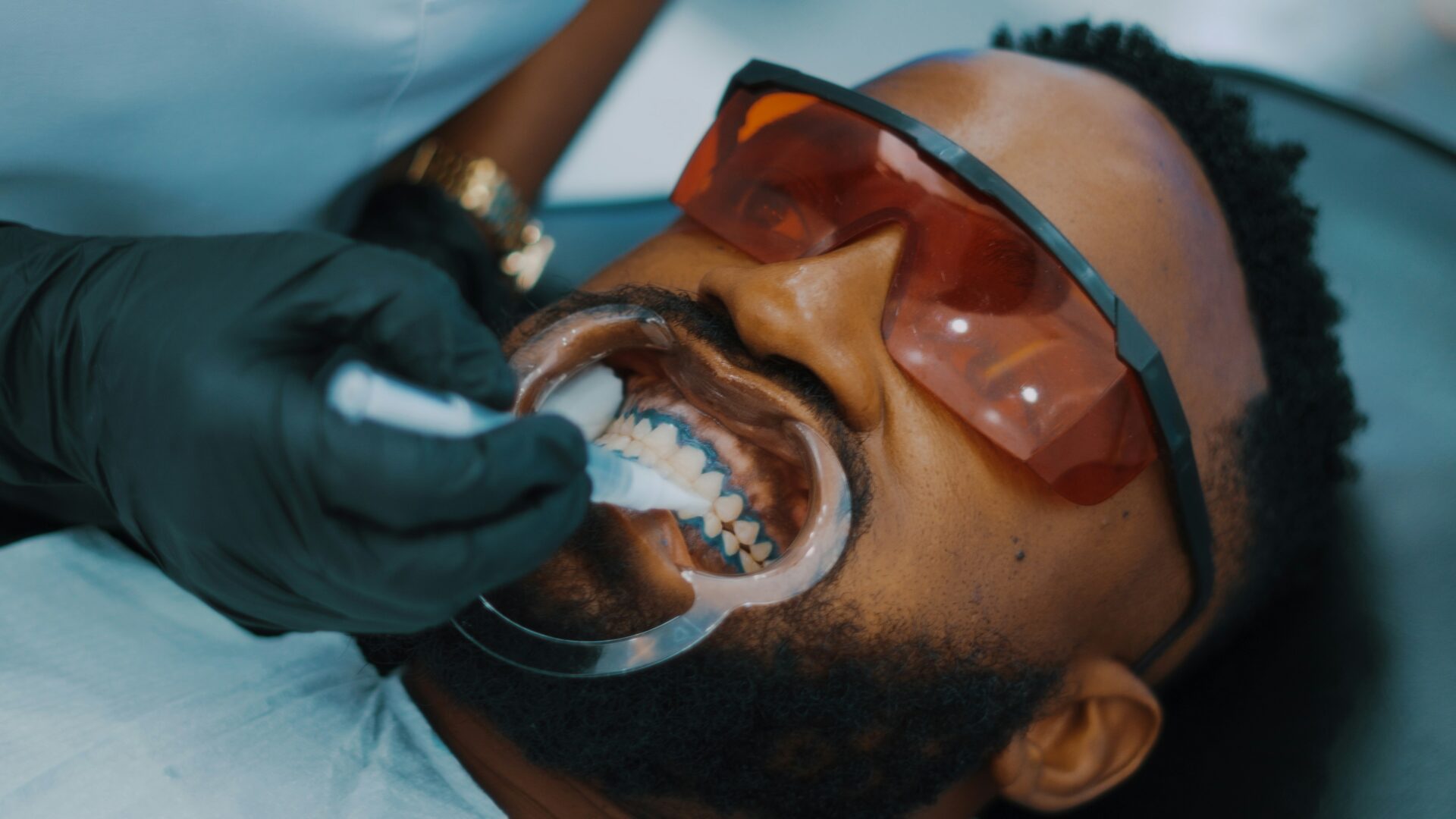 Patient receiving dental treatment with protective glasses.