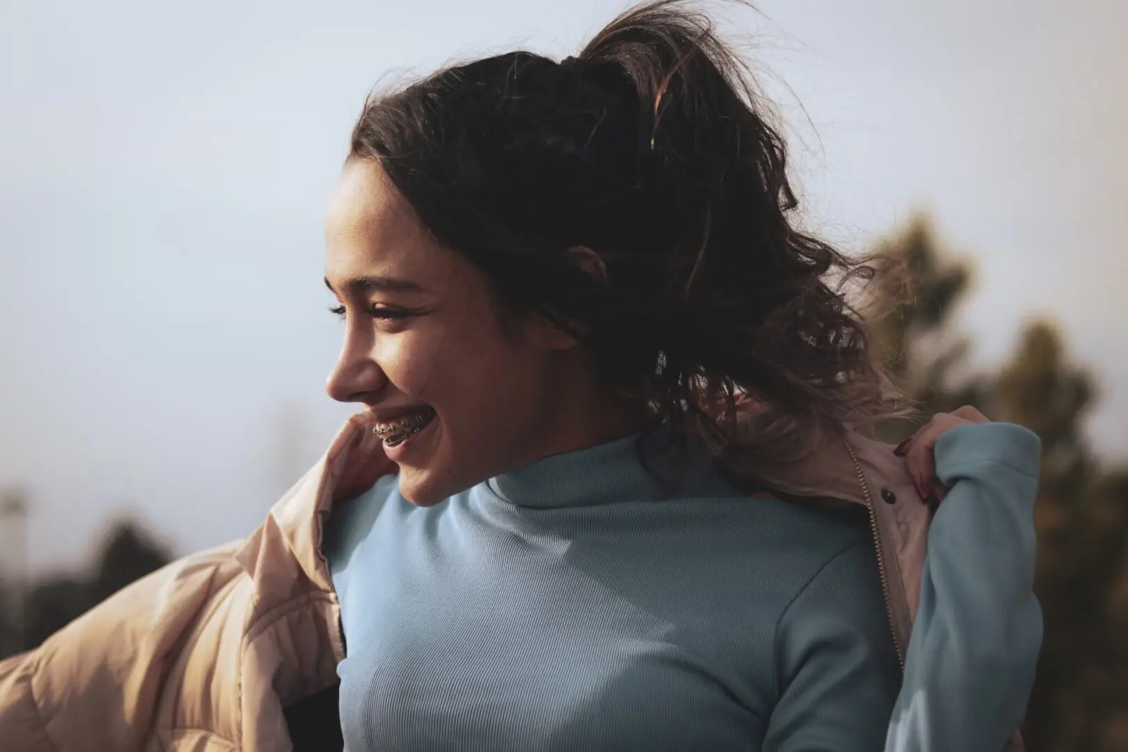 Smiling girl with braces tossing her hair.