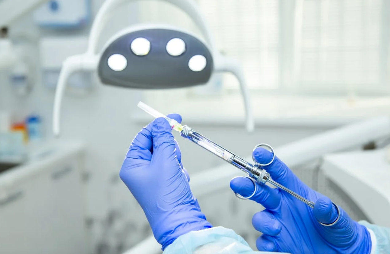 Hand holding a syringe in dental setting.