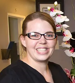 Smiling woman with glasses and flowers.